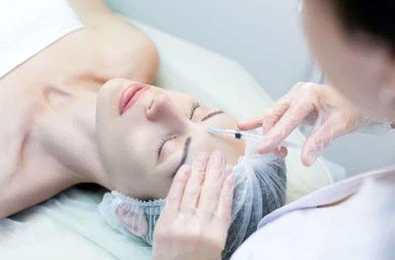 Woman laying back and receiving Dysport injections from an expert medical professional to relax wrinkles.